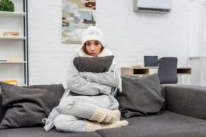 woman-wrapped-in-robe-holding-pillow-looking-cold