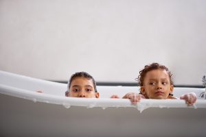 Two kids enjoying a warm bath, made possible by recent hot water heater installation.